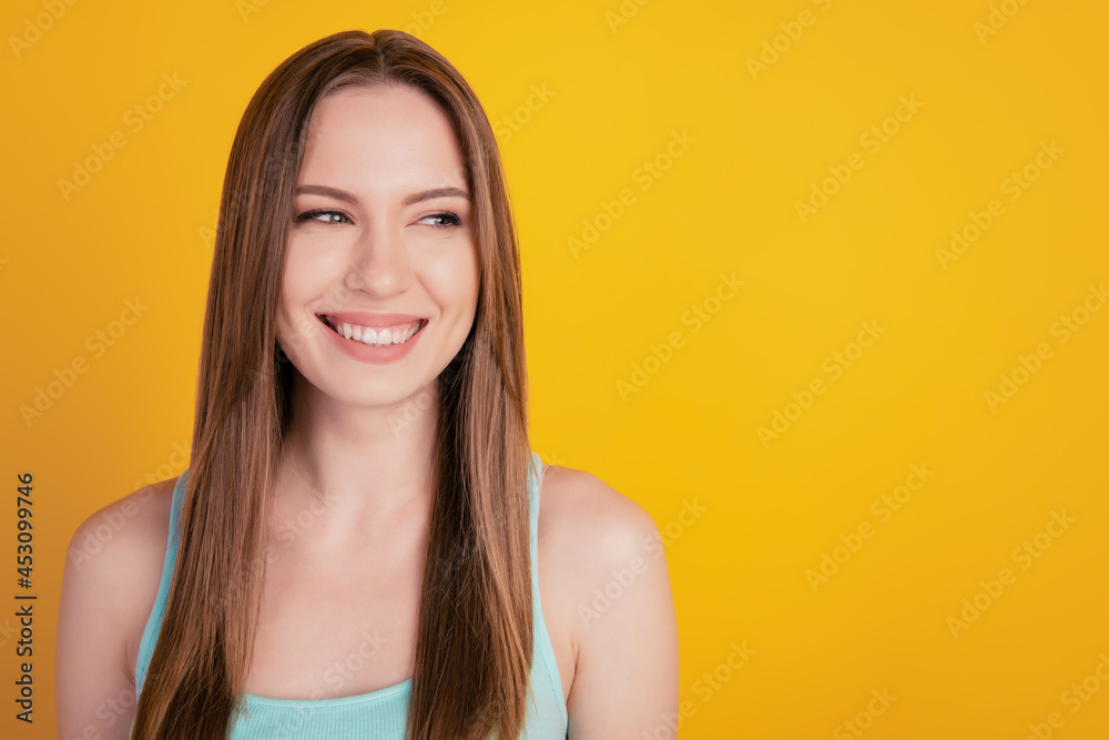 Portrait of lovely curious cheerful young lady white smile look side empty space on yellow background Portrait of lovely curious cheerful young lady white smile look side empty space on yellow background