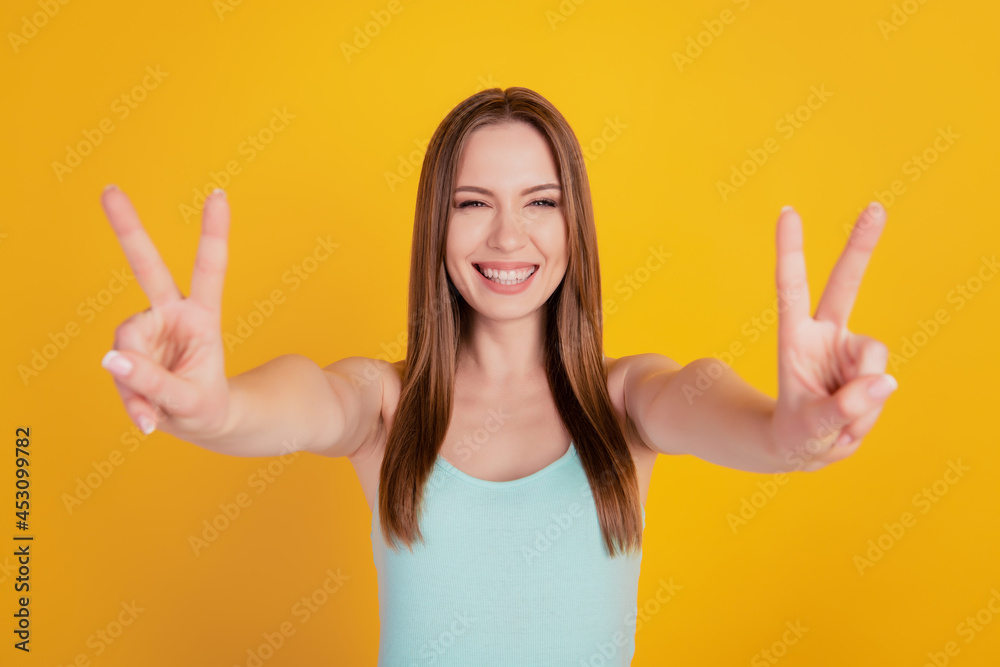 Portrait of pretty lovely friendly lady show two v-signs toothy white smile on yellow background Portrait of pretty lovely friendly lady show two v-signs toothy white smile on yellow background