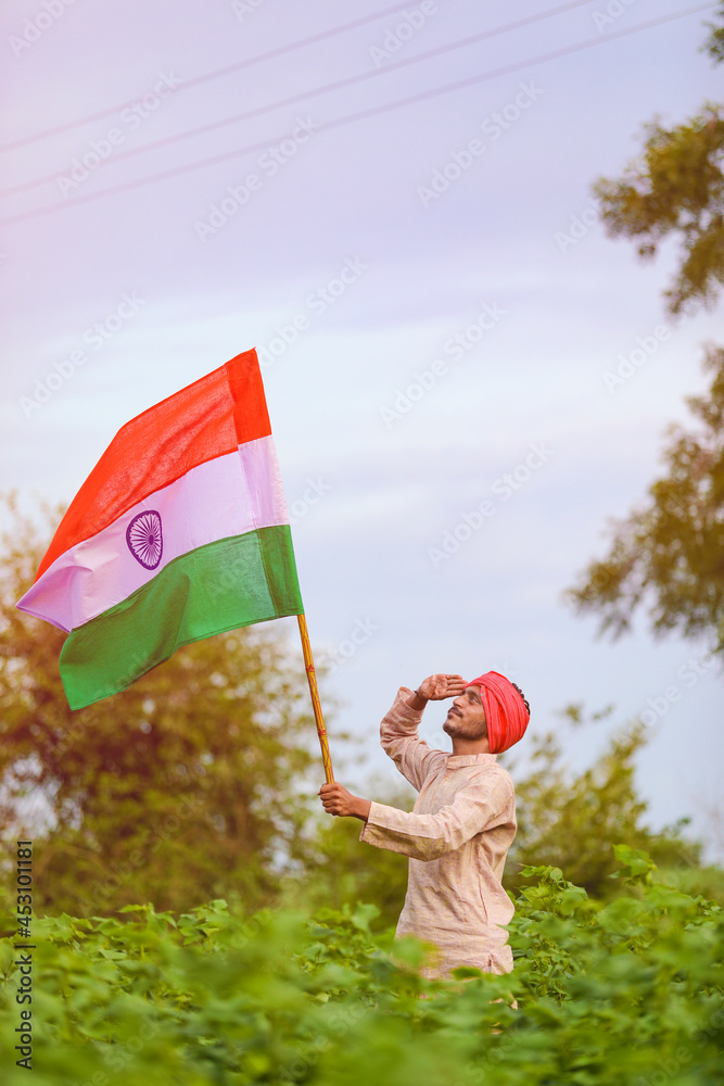 young indian farmer holding indian flag in hand at agriculture field ...