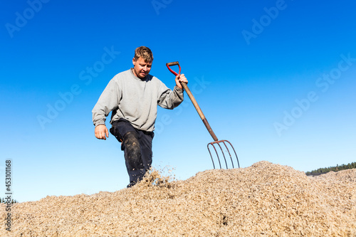Male farmer with pitchfork working during harvest photo