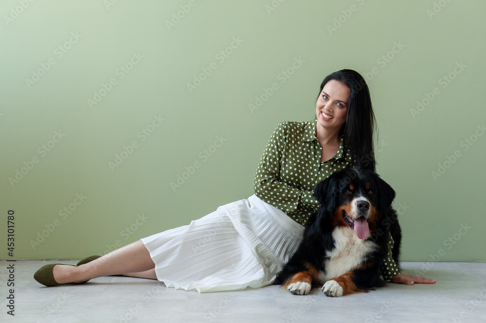 Berner Sennenhund dog and a girl in a green blouse lie on the floor