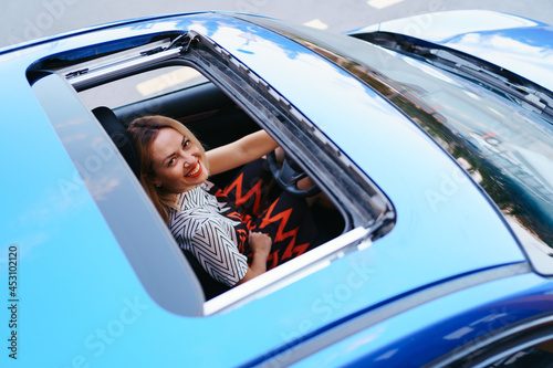 Young woman driving with sunroof open photo