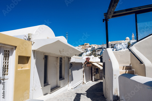 Empty narrow street in Thira, Santorini island. Closed shops during coronavirus lockdown. White greek architecture/