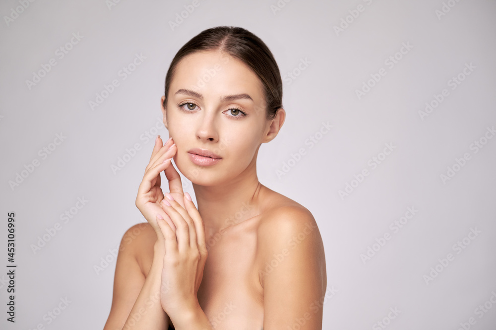 Beautiful Young Woman with Clean Fresh Skin standing over light grey background Beautiful Young Woman with Clean Fresh Skin standing over light grey background
