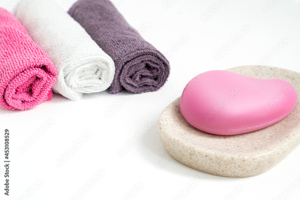 Piece of pink soap on tray and colorful rolled towels on bathroom table Piece of pink soap on tray and colorful rolled towels on bathroom table