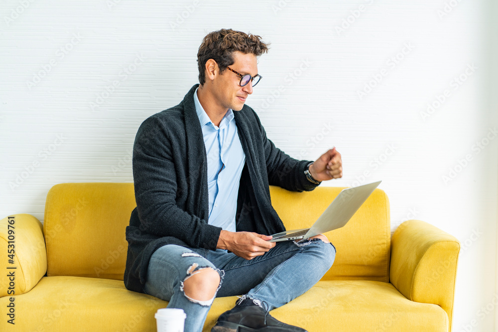 male executive sits on a sofa, is quarantined at home, reads paperwork reports and has a conference with colleagues in the living room at home. Work from home concept.