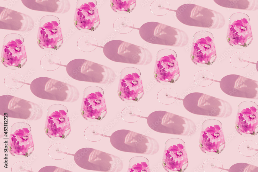 Creative pattern made of glass with hibiscus flower water on pastel pink background with sunlit. Summer and refreshment concept. Minimal style