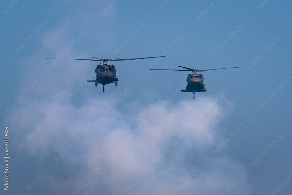 Fototapeta premium American Black Hawk helicopter Sikorsky UH - 60M attack takes off at the operation with weapons between smoke in battle war