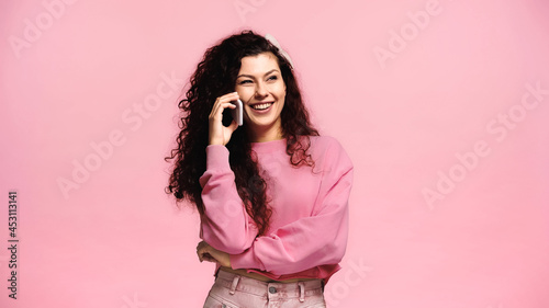 excited woman smiling during conversation on cellphone isolated on pink © LIGHTFIELD STUDIOS