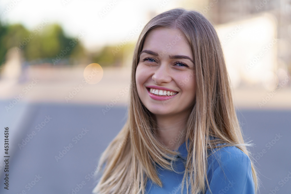 Attractive cheerful blonde girl with flying long hair smiling laughing in the city