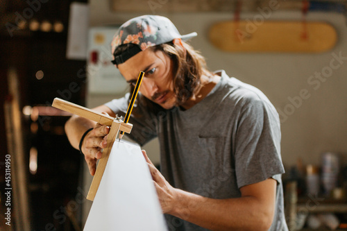 Focused male surfboard shaper suing scribe tool photo
