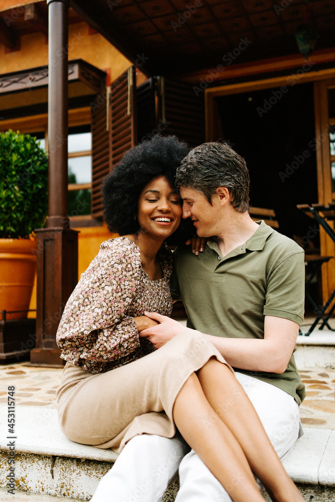 Loving multiethnic couple hugging on porch of house Loving multiethnic couple hugging on porch of house