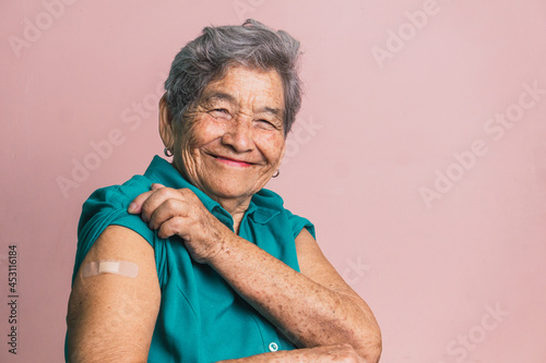 Aged woman with plaster on arm after vaccination from coronavirus photo