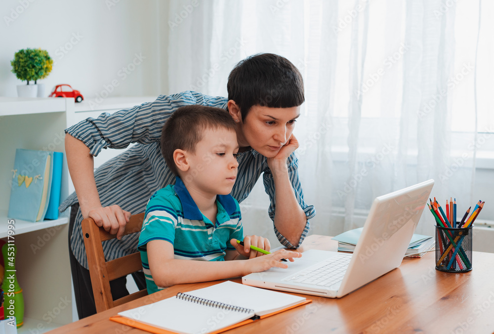 Mother and child school student at home on a laptop learning homework. e-home schooling during the period of the pandemic and coronavirus. Mother and child school student at home on a laptop learning homework. e-home schooling during the period of the pandemic and coronavirus.