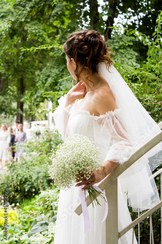 A beautiful bride in a white dress and with a bouquet is waiting for the groom