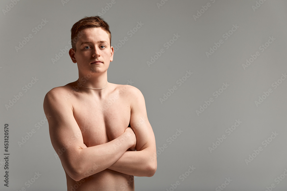 Young attractive swimmer in excellent physical shape in purple swimming shorts, on a gray background, copy space