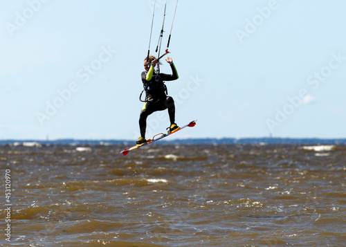 Kitesurfer female make trick in air over water surface