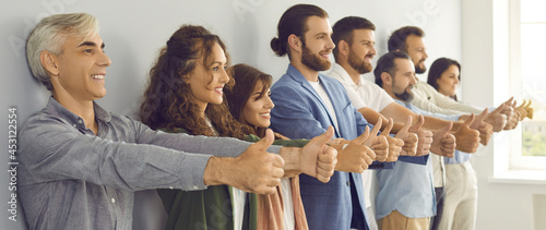 Foto Team of smiling modern business people doing like gesture together