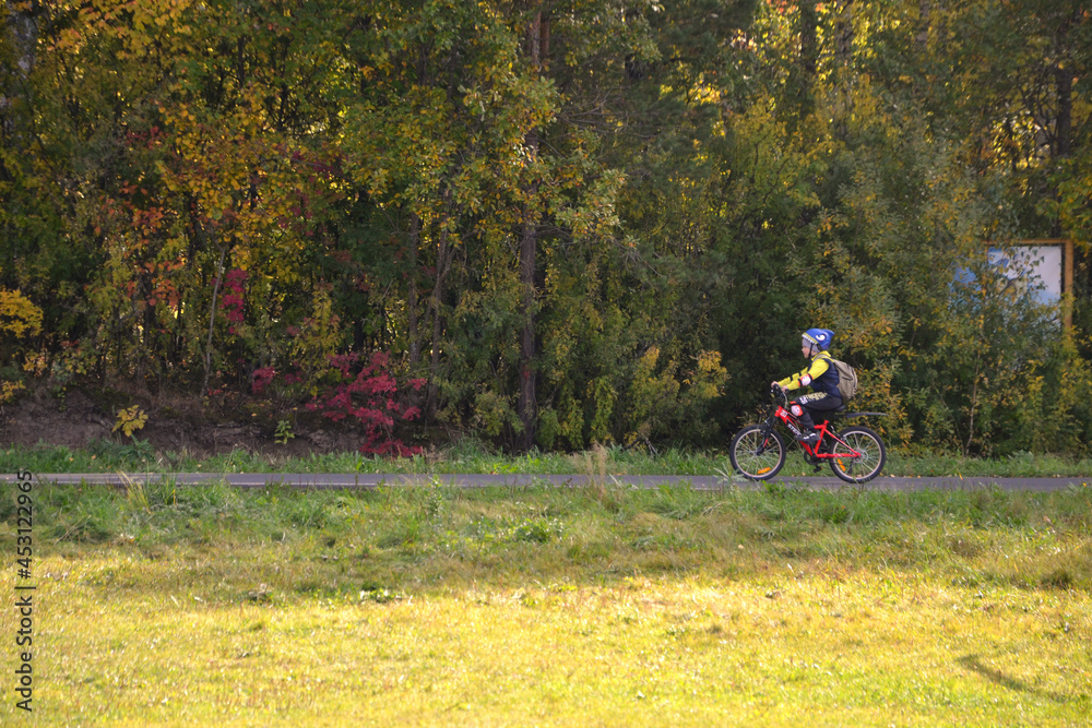 Boy riding a bike in the park in early autumn