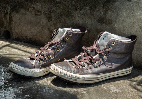Brown Retro High Top Canvas Sneakers was placed on old cement floor. Vintage age-worn sneakers canvas shoes brown, Concept : Sometimes the long journey of life should rest. Copy space, Selective focus