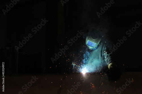 An electric welder welds metal structures at a factory. photo