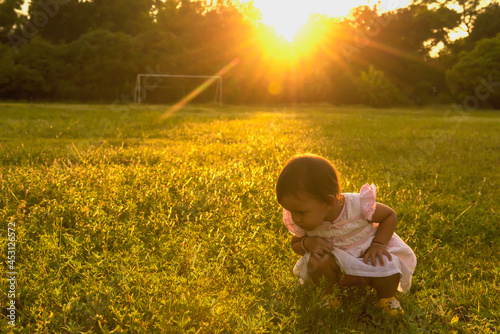 Foto A little girl in the lawn looks at the spider closely at sunset