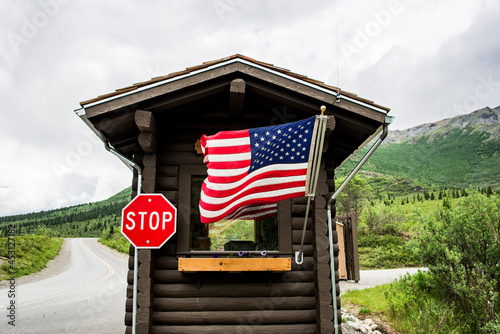 USA, Alaska, American flag and stop sign on cabin photo