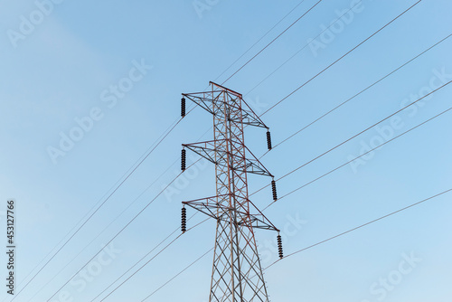 High-voltage power lines electricity transmission pylon on blue sky background.