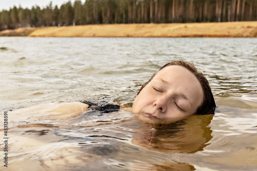 Fototapeta premium Portrait of a young woman close-up in the water. Swimming in the lake