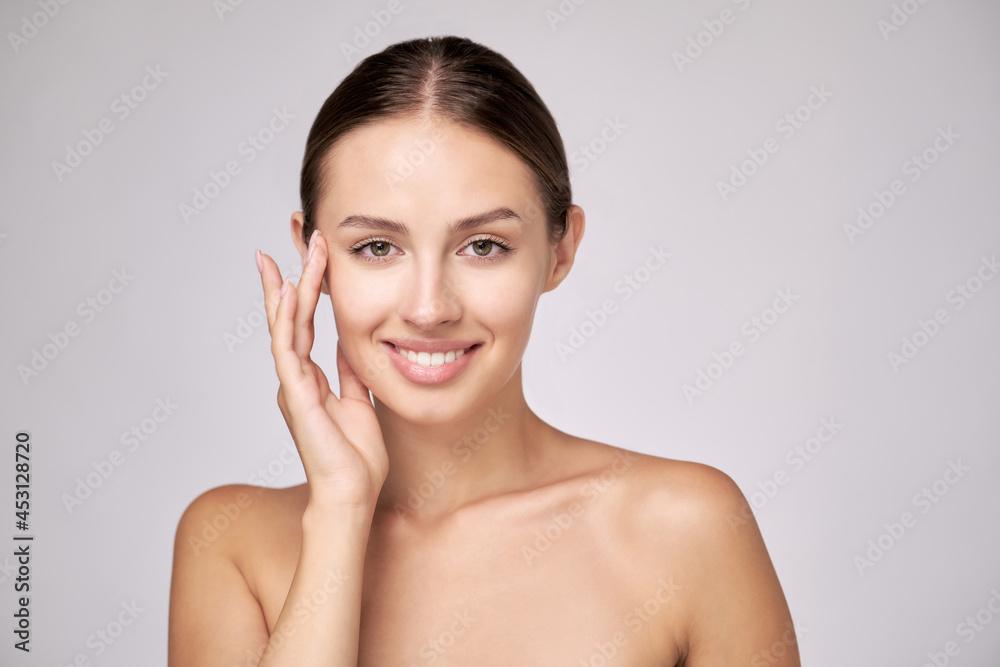 Beautiful Young Woman with Clean Fresh Skin standing over light grey background