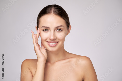 Beautiful Young Woman with Clean Fresh Skin standing over light grey background