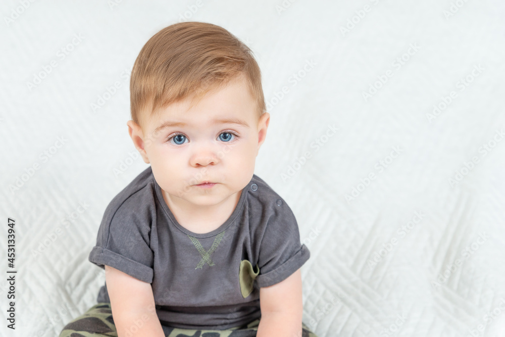 Naklejka premium Close-up portrait of a nine-month-old baby boy over white background. Adorable red haired kid looking at camera. Copy space.