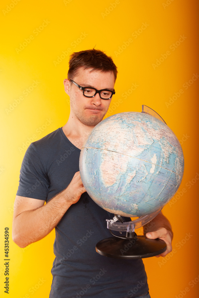 Portrait of stylish joyful teacher in jacket holding round globe, earth in hands, looking at camera and object, isolated on yellow background Portrait of stylish joyful teacher in jacket holding round globe, earth in hands, looking at camera and object, isolated on yellow background