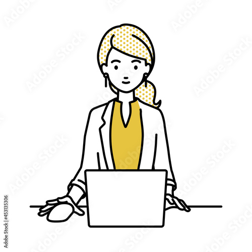 デスクで座ってPCを使っているジャケットの女性