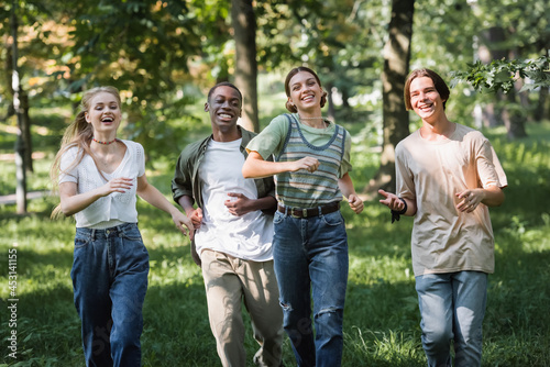 Happy multiethnic teenagers running on grass in park