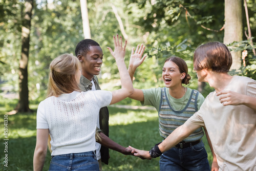 Cheerful interracial teen friends giving high five outdoors © LIGHTFIELD STUDIOS