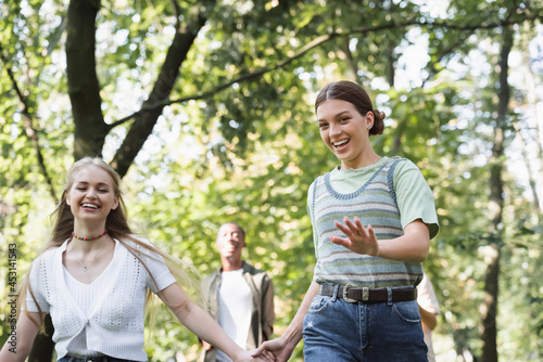 Smiling girl holding hand of teen friend in park