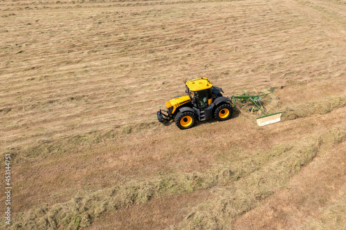 Tractor raking cut hay in field