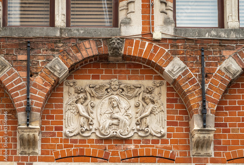 Brugge, Flanders, Belgium - August 4, 2021: Closeup of white fresco showing Mater Dolorosa, Moeder van Smerten, against red brick background under arch on facade of house.