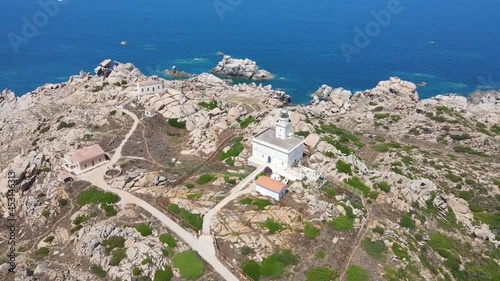 Flight around the white building of the lighthouse, which stands on a cliff next to the azure sea