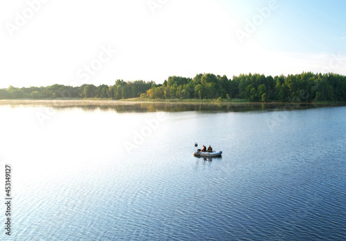 Fishermen in a boat fishing in the lake. Fishing for river fish from a motor boat using a fishing rod or spinning rod. Sports fishing on the water. Rest in the wild