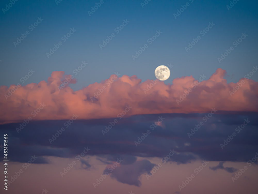 The moon at the sunset with red and pink clouds The moon at the sunset with red and pink clouds