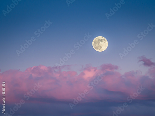 The moon at the sunset with red and pink clouds © Andrea