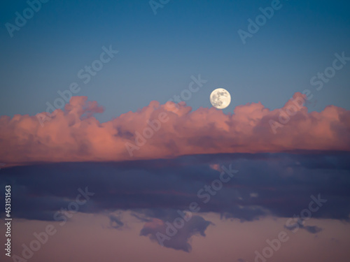 The moon at the sunset with red and pink clouds © Andrea