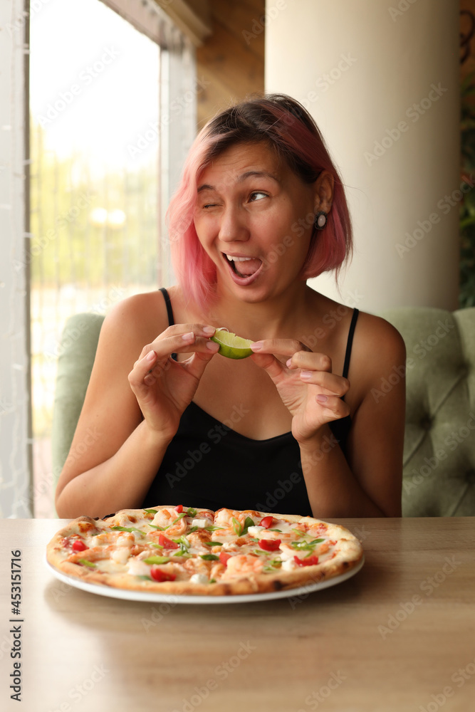 A cheerful girl is going to eat a seafood pizza A cheerful girl is going to eat a seafood pizza