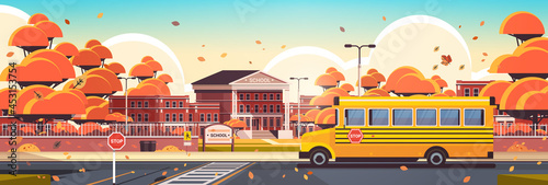 school building empty front yard with trees road crosswalk and school bus autumn cityscape
