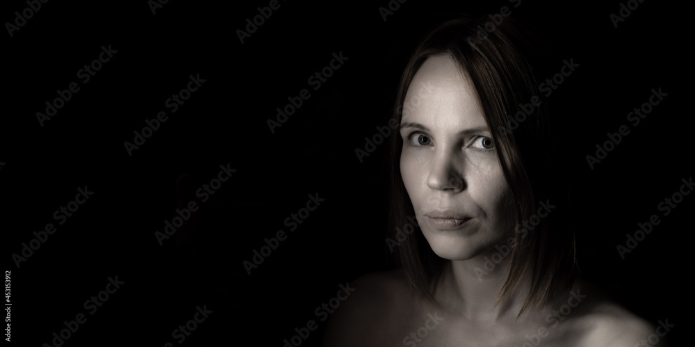 Portrait of 40 year old adult woman without makeup on black background.