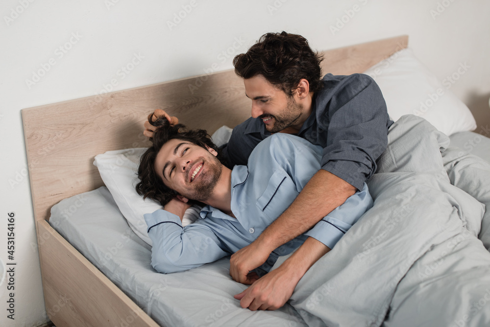 happy gay man adjusting hair of boyfriend in bed happy gay man adjusting hair of boyfriend in bed