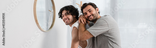 man hugging cheerful boyfriend in bathroom, banner