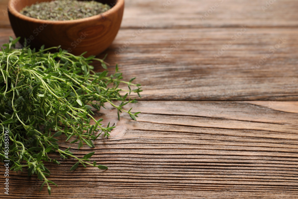 Bowl with dried thyme and fresh herb on wooden table. Space for text Bowl with dried thyme and fresh herb on wooden table. Space for text